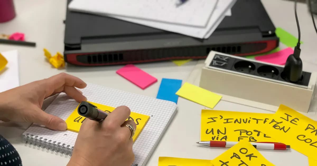 A designer developing ideas with sticky notes beside a laptop