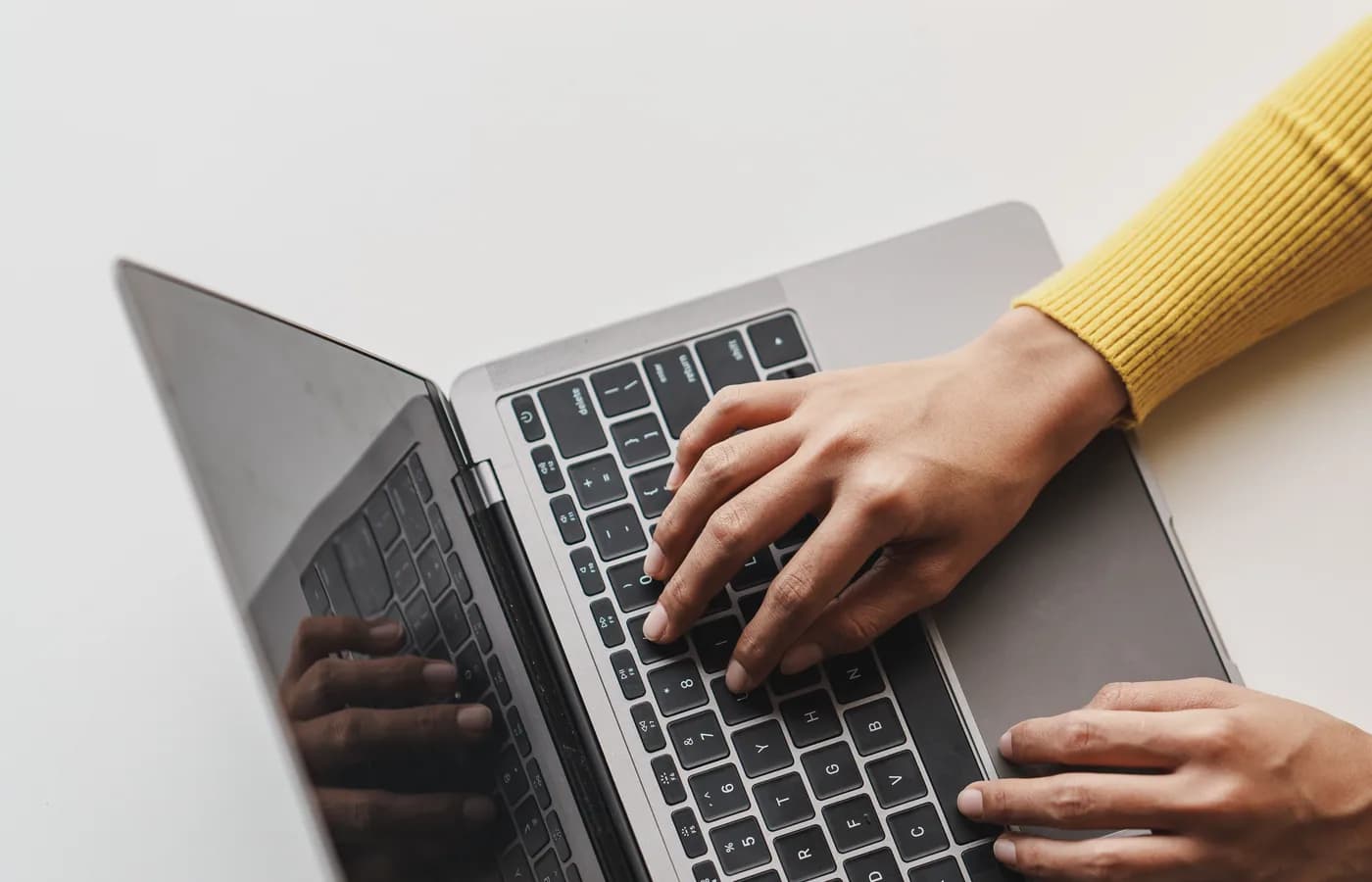 Hands working on a laptop in a bright workspace