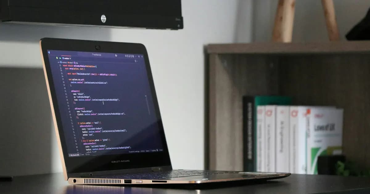 Software source code displayed on a laptop at a desk
